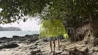 母亲和她的女儿在<strong>烈日</strong>下用一块大布走在一起。 一起在海岸上散步。
